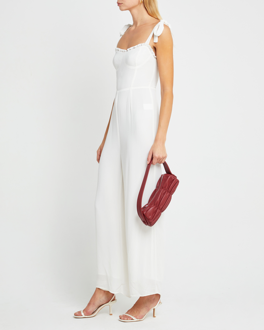 Third image of Blair Jumpsuit, a white jumpsuit with straight-leg lined pants, adjustable tie straps, cup detail, neckline ruffles, and a back zipper