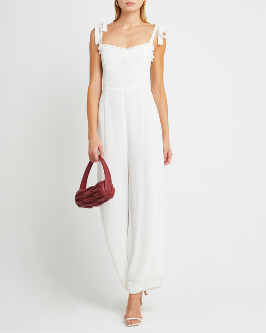 First image of Blair Jumpsuit, a white jumpsuit with straight-leg lined pants, adjustable tie straps, cup detail, neckline ruffles, and a back zipper